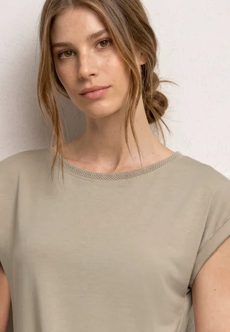 Gros plan d’une femme en t-shirt beige sur fond blanc.