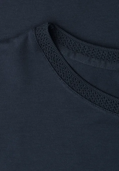 Close-up van de kraag van een donkerblauw T-shirt met stikseldetail.