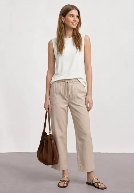 Top im U-Boot-Ausschnitt off white Eine Frau trägt ein weißes Top, beige Hosen und Sandalen und hält eine braune Handtasche.