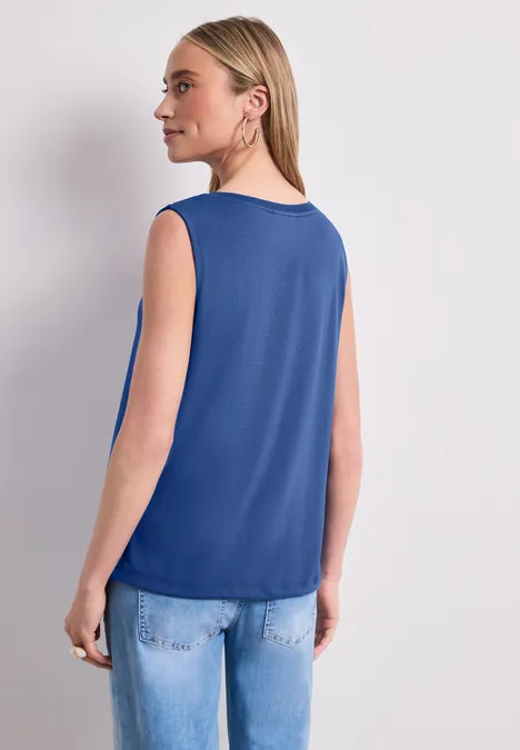 Top col bateau amparo blue Femme de dos portant un haut bleu sans manches et un jean