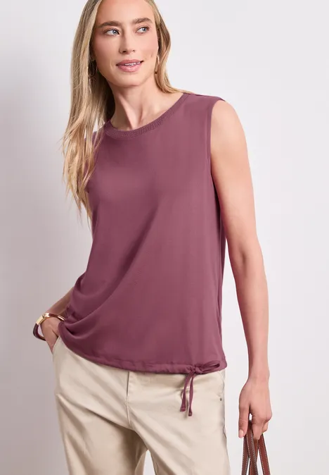 Top im U-Boot-Ausschnitt dark clouded blush Model trägt ärmelloses, violettes Top mit Kordelzugbund und beige Hose.