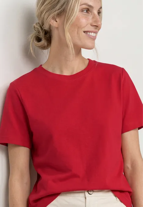 Frau in rotem T-Shirt vor neutralem Hintergrund