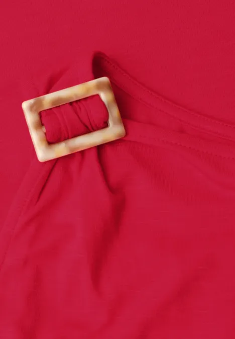 Rotes Top mit einer beigen, rechteckigen Schnalle am Träger.