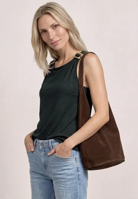 Frau trägt schwarzes Top, Jeans und braune Schultertasche.