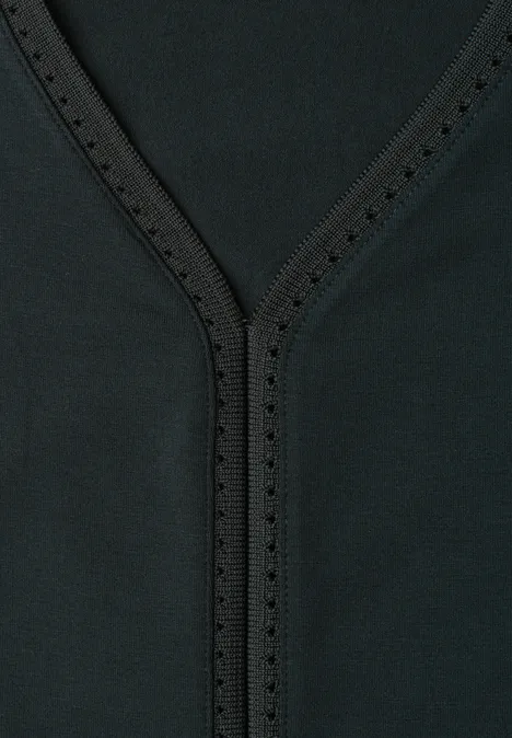 Close-up van een zwarte V-hals met siersteken en kleine perforaties