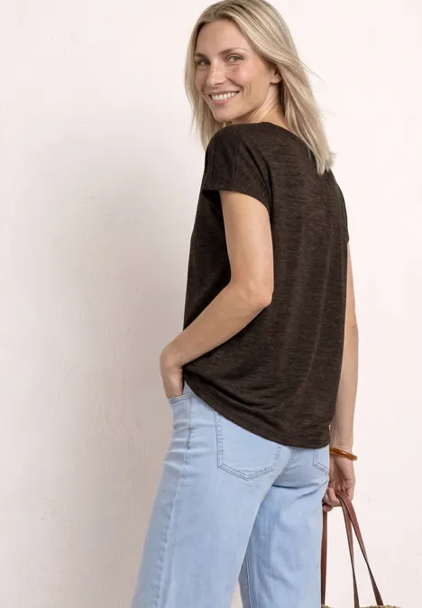 Achteraanzicht van een vrouw in bruin t-shirt en lichtblauwe jeans met leren tas voor een lichte achtergrond.