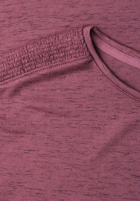 Close-up van een bordeaux T-shirt met zichtbare naad bij de halslijn.