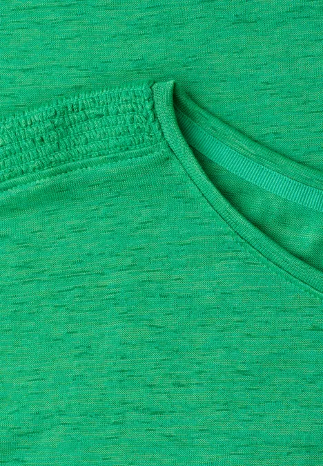 Close-up van een groen T-shirt met ronde hals en subtiele melering.