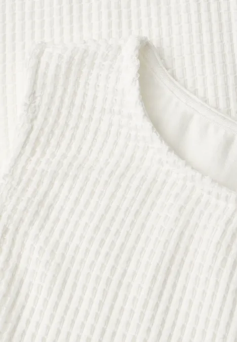 Nahaufnahme eines weißen, gerippten Gewebes mit rundem Ausschnitt.