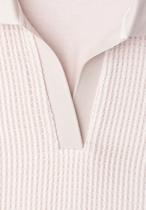 Nahaufnahme eines hellbeigen Strick-Polohemds mit V-Ausschnitt und feiner Textur