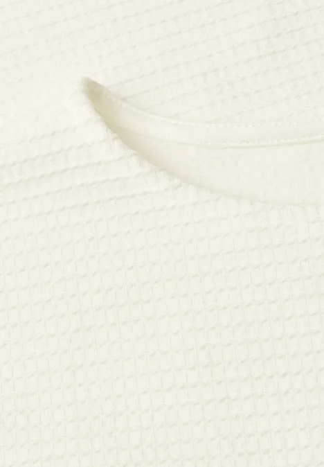 Nahaufnahme eines weißen T-Shirts mit Waffelstrickmuster und rundem Ausschnitt.