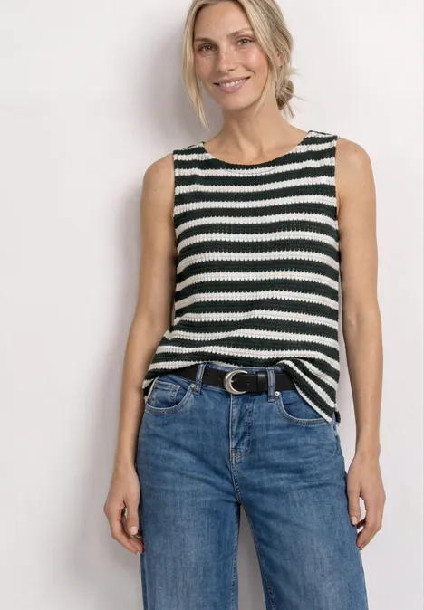 Frau in ärmellosem schwarz-weiß geringeltem Top und blauen Jeans mit Gürtel.