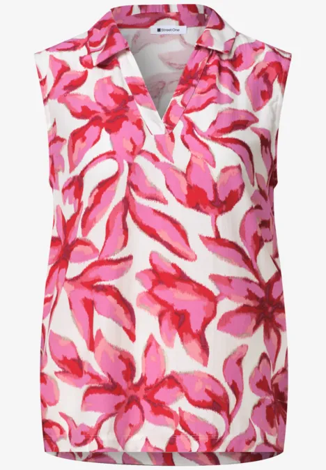 Débardeur sans manches col V, fond blanc à motif floral rose vif.