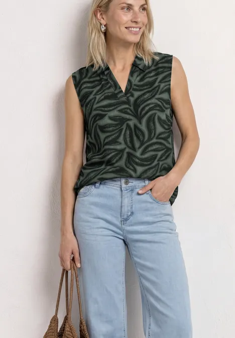 Top mit Kragen und Strukturmix deep bound green Frau in dunkelgrüner, gemusterter ärmelloser Bluse, V-Ausschnitt, hellblauen Jeans, mit Handtasche.