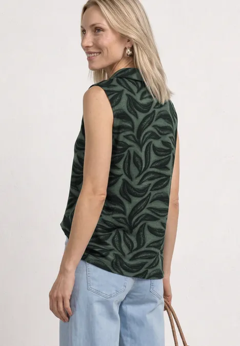 Top mit Kragen und Strukturmix deep bound green Rückansicht einer Frau in ärmellosem, schwarz-grünem Blattmuster-Oberteil, hellblauen Jeans und hellbrauner Tasche.