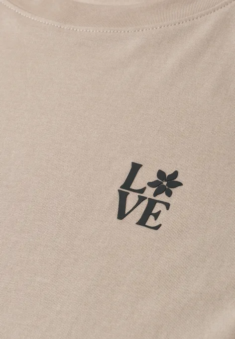 Ein beiges Shirt mit dem Schriftzug LOVE, wobei das O als Blüte dargestellt ist.