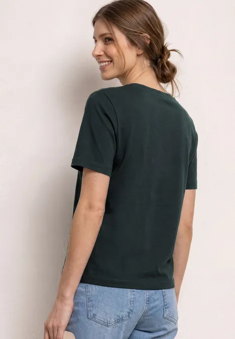 Person mit zusammengebundenem Haar trägt dunkles T-Shirt und Jeans, Rückenansicht.