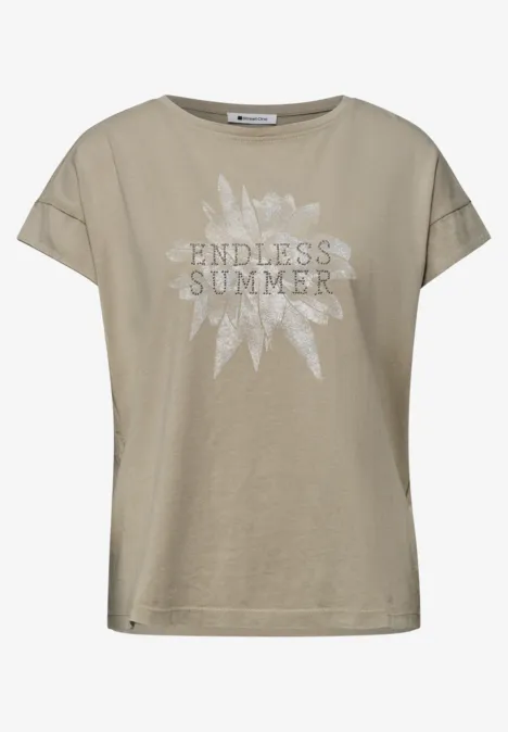 Beiges Damen-T-Shirt mit überschnittenen Ärmeln und weißem 'ENDLESS SUMMER'-Print vor Sonnenmotiv.
