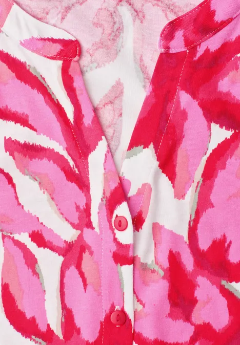 Nahaufnahme eines rosa-rot gemusterten Strickjäckchens mit abstraktem Blumenprint.