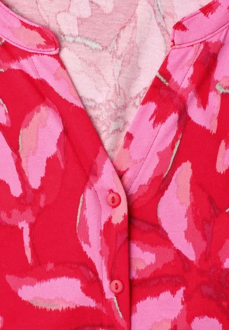 Nahaufnahme eines rot-pinken gemusterten Gewebes mit Knopfleiste