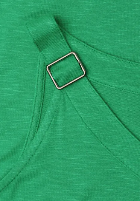 Nahaufnahme eines grünen Stoffs mit verstellbarem Träger und silberner rechteckiger Schnalle.