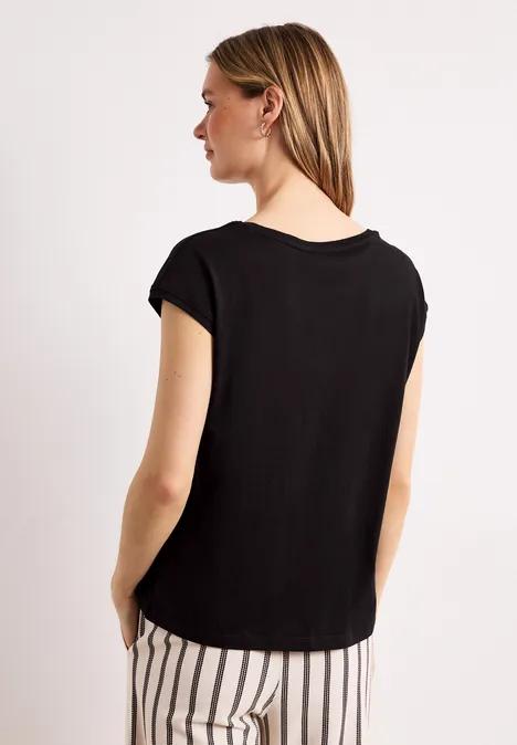 Frau von hinten in schwarzem T-Shirt und schwarz-weißer gestreifter Hose