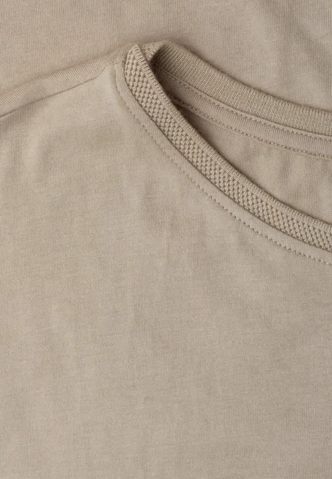 Close-up van een beige T-shirthals met zichtbare naad.