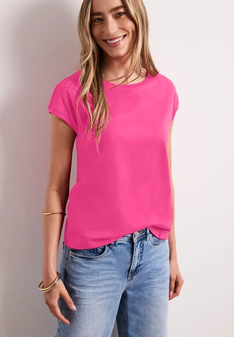 Vrouw in roze T-shirt en spijkerbroek voor witte achtergrond