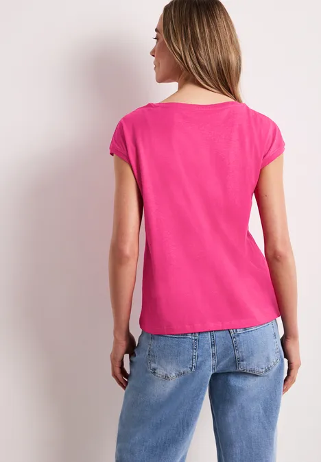Een vrouw gezien van achteren in een roze shirt en blauwe spijkerbroek.