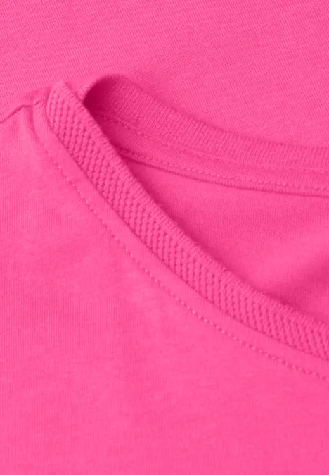 Close-up van een felroze T-shirtnek met zichtbare stiknaden en zachte katoenen stof.