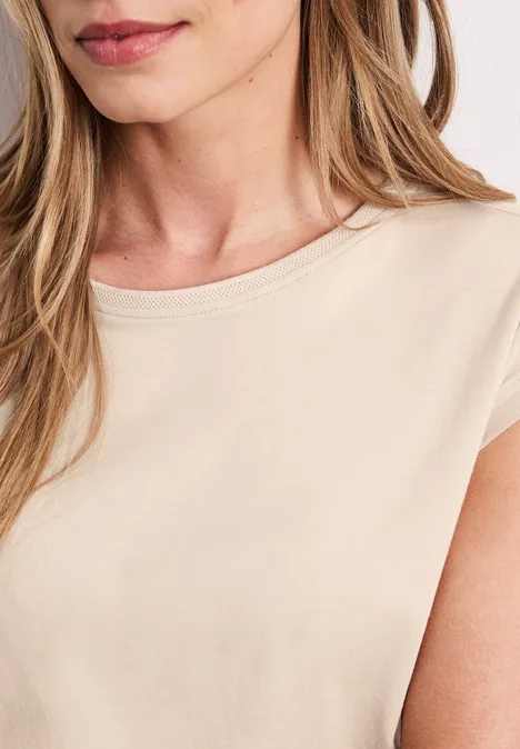 Close-up van een vrouw met blond haar, lichte glimlach, beige topje en natuurlijke make-up.