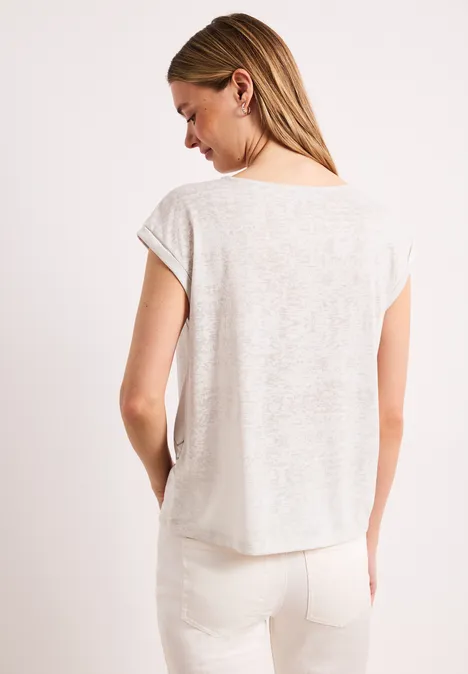 Vrouw van achteren in een licht linnen t-shirt en witte broek met achterzakken.