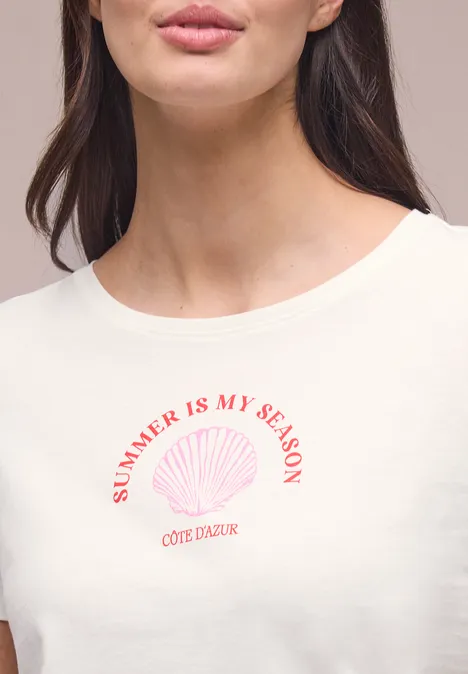 Nahe Aufnahme einer Frau im weißen T-Shirt mit 'SUMMER IS MY SEASON'-Aufdruck und Muschelmotiv.