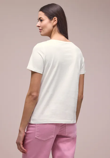 Frau steht von hinten, trägt ein weißes T-Shirt und rosa Hose.