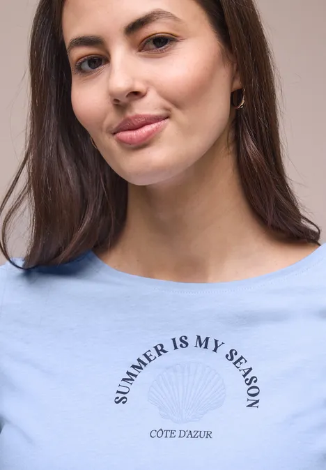 Frau in blauem T-Shirt mit Aufdruck SUMMER IS MY SEASON CÔTE D'AZUR, Gesicht unkenntlich.