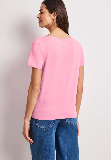 Frau in rosa T-Shirt und blauen Jeans von hinten gesehen.