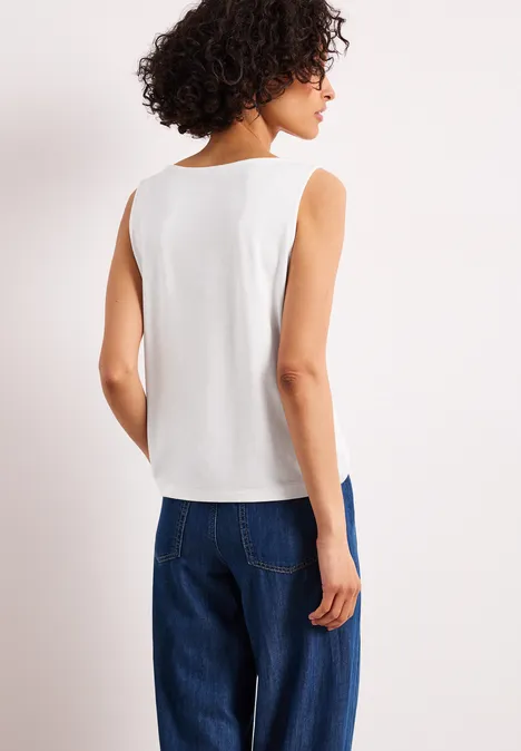 Rückansicht einer Frau in weißem ärmellosen Oberteil und blauen Jeans.