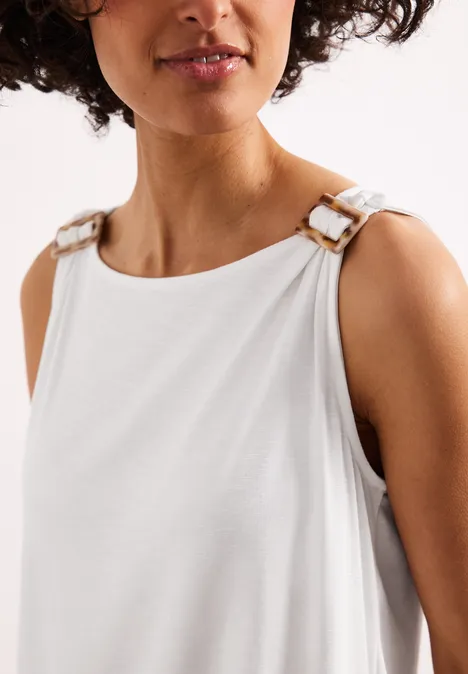 Weiße ärmellose Bluse mit goldfarbenen Schnallen an den Schultern.