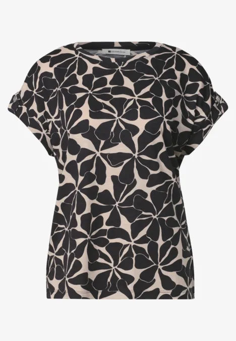 Beige shirt met losse pasvorm en zwart bloemenpatroon.