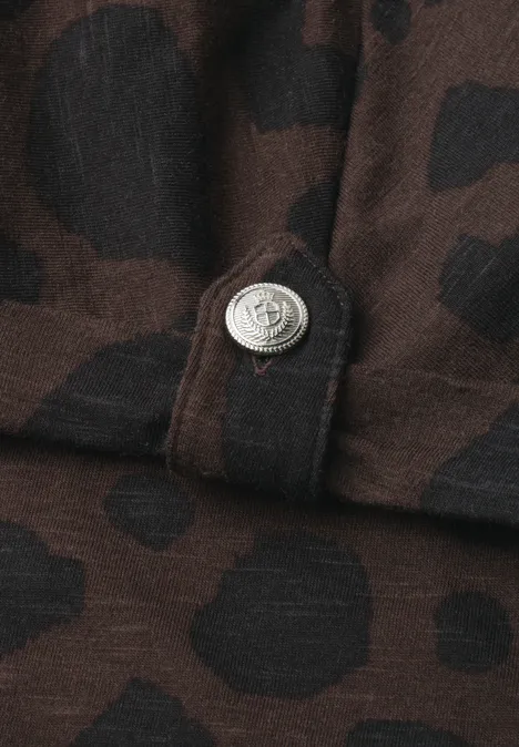 Brauner Stoff mit schwarzen, unregelmäßigen Flecken und silbernem Druckknopf.