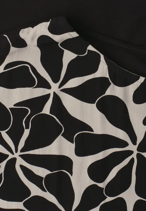 Nahaufnahme eines Kleidungsstücks mit schwarz-weißem, abstraktem Blumenmuster.