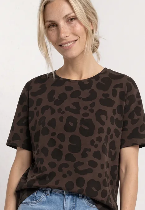 Vrouw draagt donkerbruin t-shirt met luipaardprint en een lichte jeans.