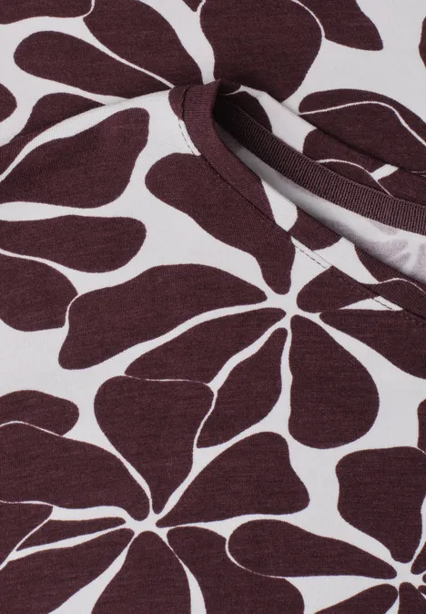 Witte stof met groot bordeaux bloemenpatroon en een split met decoratieve strik.