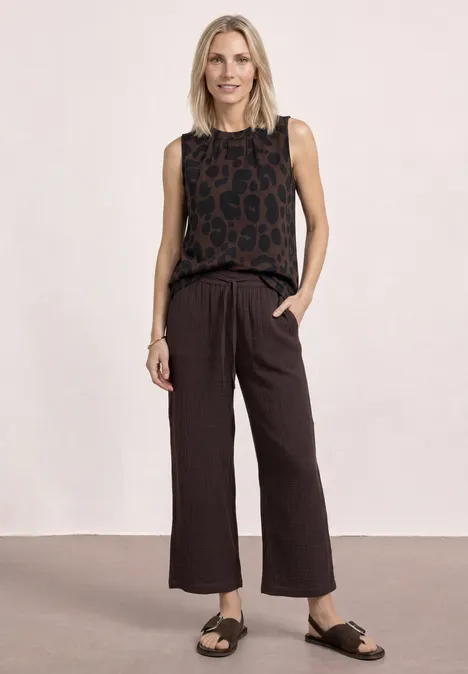 Top à col rond et imprimé zèbre molten earth Frau trägt ärmelloses Leo-Top, weite Hose und Sandalen