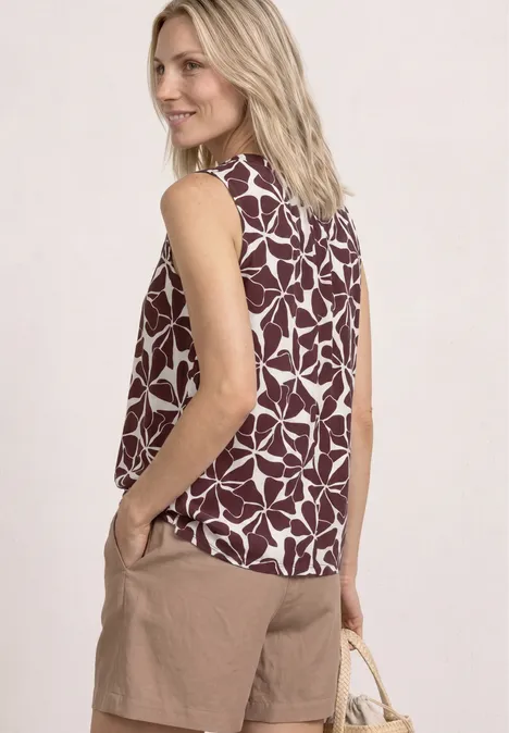 Mouwloze top met bordeaux-witte bladprint, beige short en een strozak.