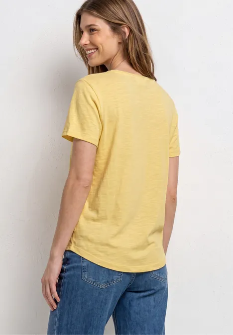 Femme vue de dos portant un t-shirt jaune et un jean bleu.