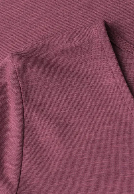 Close-up van een bordeauxkleurige jerseystof met fijne structuur en schoudernaden.