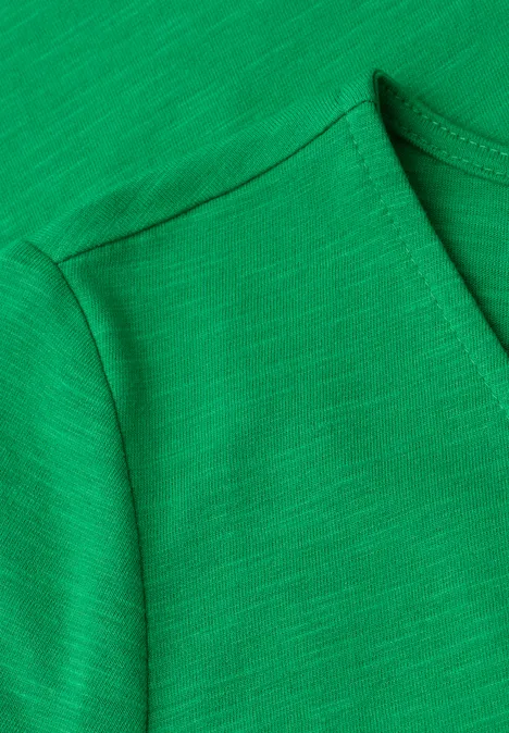 Close-up van een groen T-shirt met zichtbare schoudernaden en ronde halslijn.