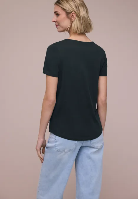 Vrouw van achter in zwart t-shirt en lichtblauwe spijkerbroek.