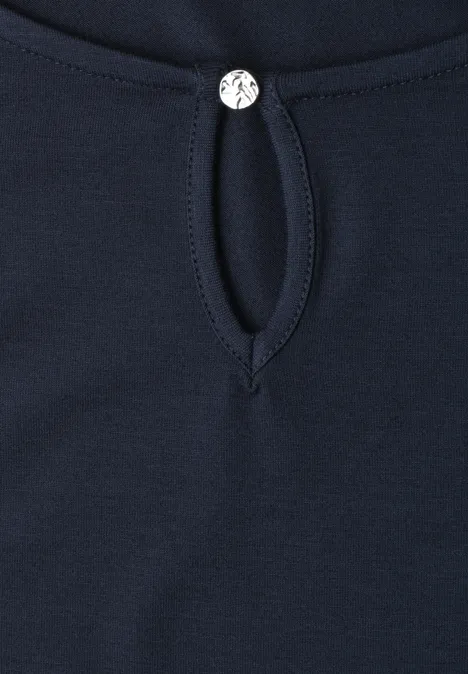 Tissu bleu marine avec encolure goutte d'eau et petit bouton argenté au col.